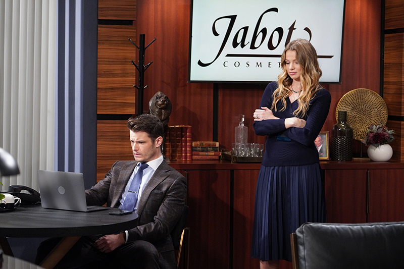a frustrated summer newman crosses her arms and looks on at kyle abbott as he stares at his computer in jack's office at jabot