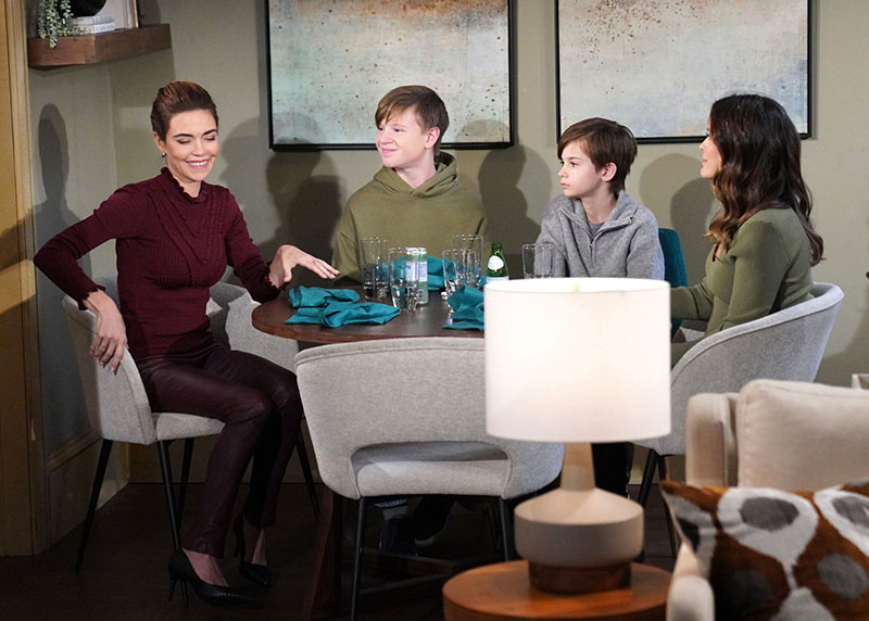victoria sits at a table and smiles as johnny connor and chelsea look at her