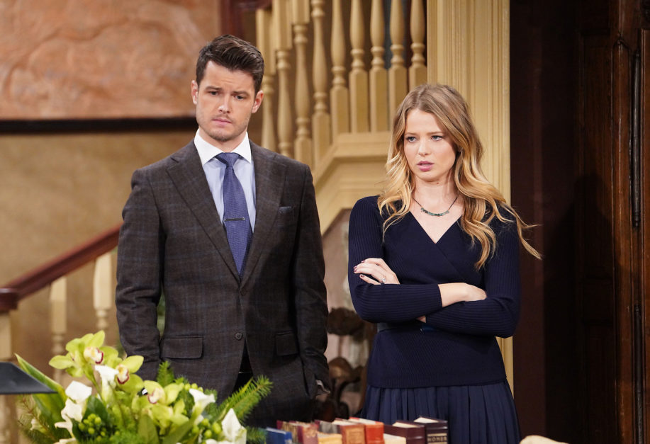 kyle abbott wearing a gray suit and blue tie summer newman abbott wearing a dark dress with her arms crossed
