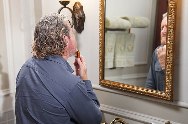 cameron looks in the mirror and compliments himself.