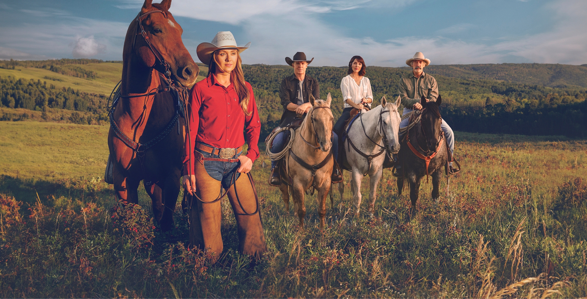 Heartland season 19 cast on horseback in a field.